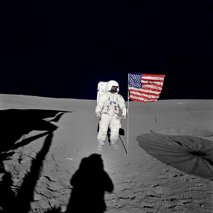 Edgar stands with the United States’ flag on the Moon