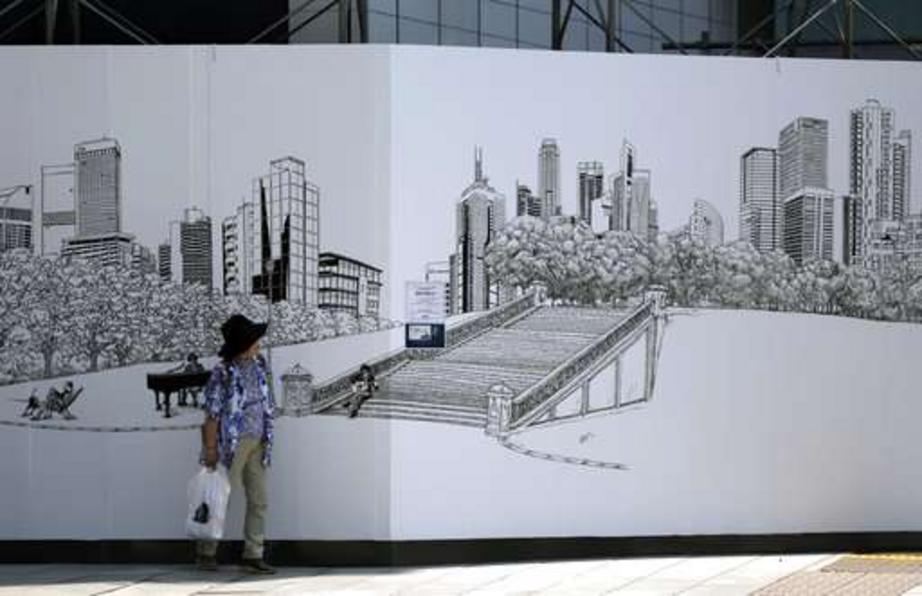  A woman stands next to a wall, with a drawing of a town scenery as the screen to hide a construction site at Ginza shopping district Thursday, June 15, 2017, in Tokyo.