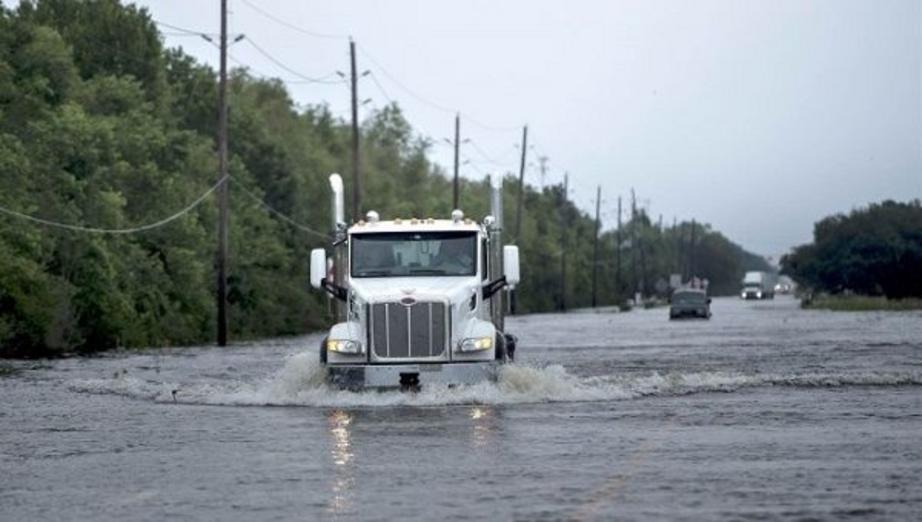 Trucks drive on the flooded road to the chemical plant where explosions were reported Thursday morning. | Photo: AFP