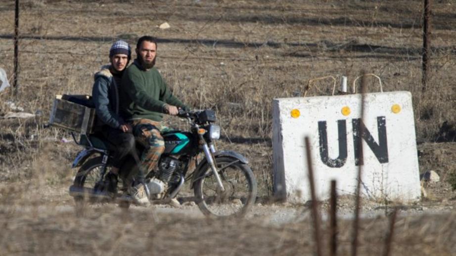 Two men, not specified which group of rebels, ride a motorcycle towards an abandoned UN base at Syria’s Quneitra border crossing between Syria and the Israeli-controlled Golan Heights, Nov. 28, 2016. (AP/Ariel Schalit)