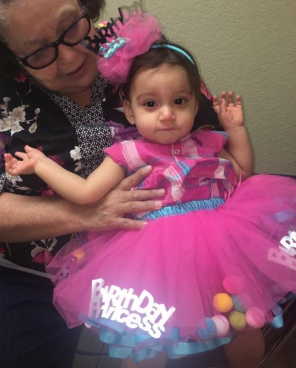 Her eyes show that she wasn’t feeling well on her birthday. Grandma Mary holds Aniya. 