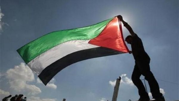 A Palestinian holds the national flag. | Photo: Reuters