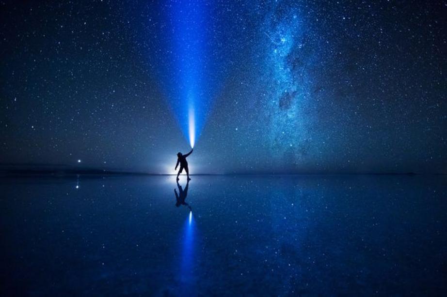 Photographer and light artist Eric Paré shines a light into the sky above the salt flats of Bolivia