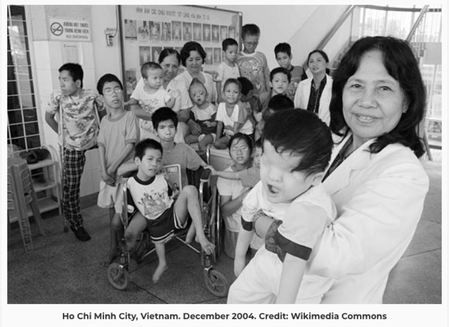 Professor Nguyen Thi Ngoc Phuong poses for a photo with the handicapped children under her care. Every one of them was born with a defect caused by Agent Orange.