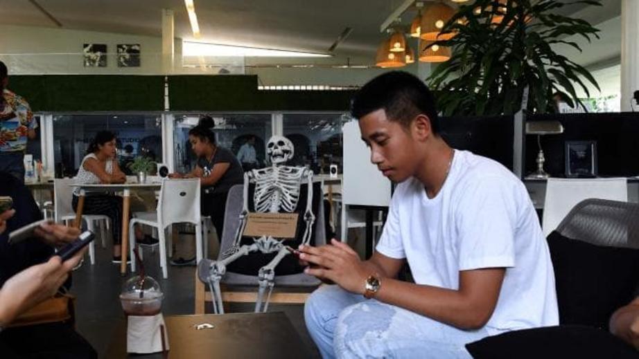 Patrons enjoy drinks next to a skeleton.